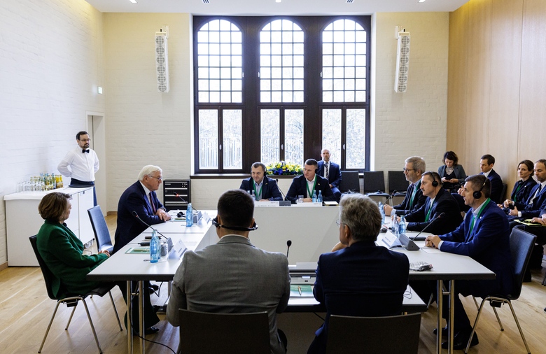 Bundespräsident Steinmeier sitzt mit sieben weiteren Personen an einem großen Tisch